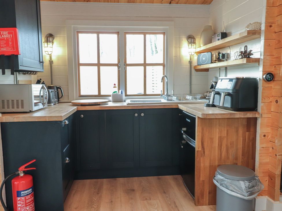 A kitchen with a sink and shelves at Caban Tan Y Dderwen in Chwilog