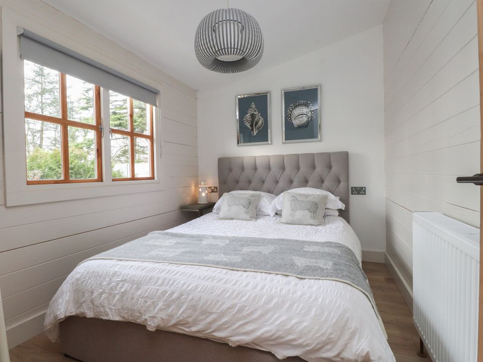 A bedroom with a bed and wall art at Caban Tan Y Dderwen in Chwilog