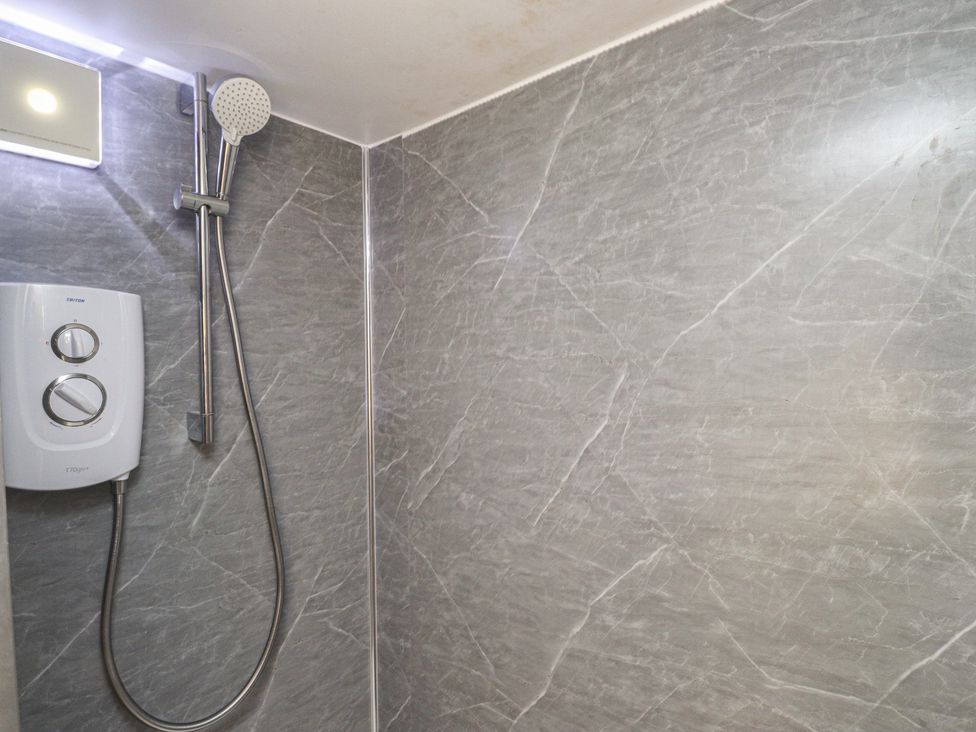 A shower with a showerhead and control unit at Caban Tan Y Dderwen Chwilog
