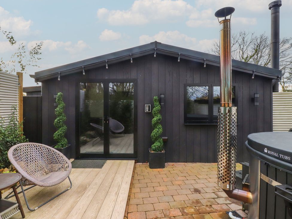 An outdoor area with a hot tub and seating at Caban Tan Y Ffawydd in Chwilog near Y Ffor