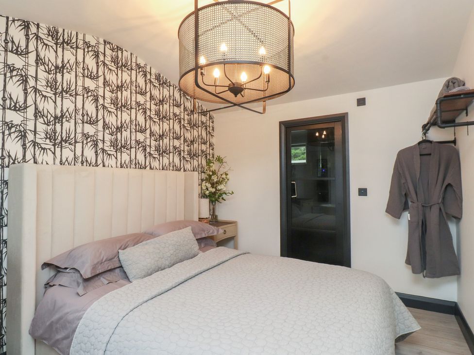 A bedroom with a bed and a bedside table at Caban Tan Y Ffawydd in Chwilog near Y Ffor