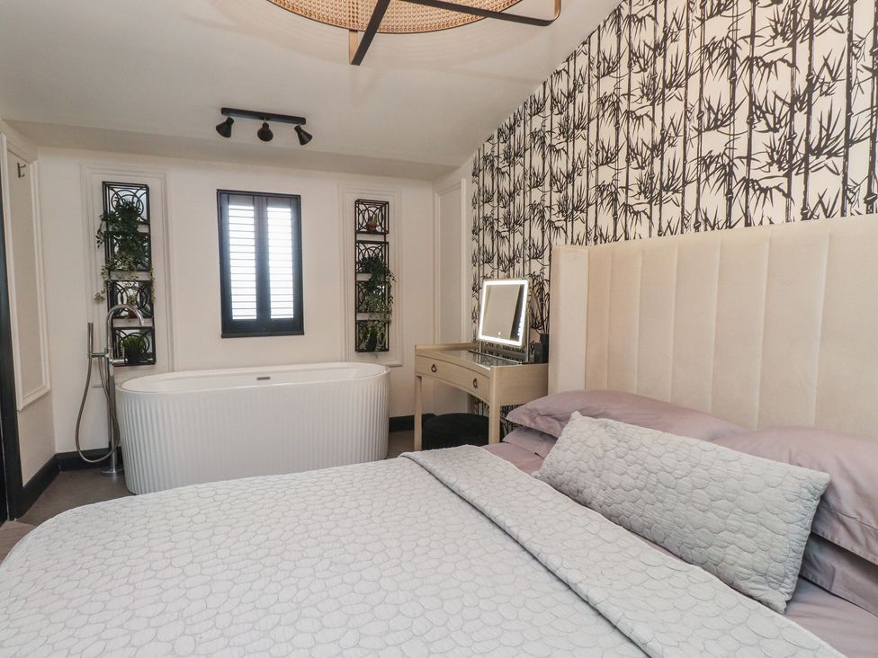A bathroom with a bathtub and a mirror at Caban Tan Y Ffawydd in Chwilog near Y Ffor