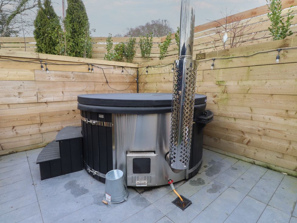 A hot tub on a patio in an outdoor area at Riverside Lodge Afonwen