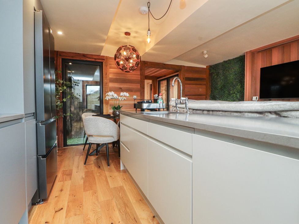 A kitchen with a refrigerator and a kitchen island at Riverside Lodge in Afonwen