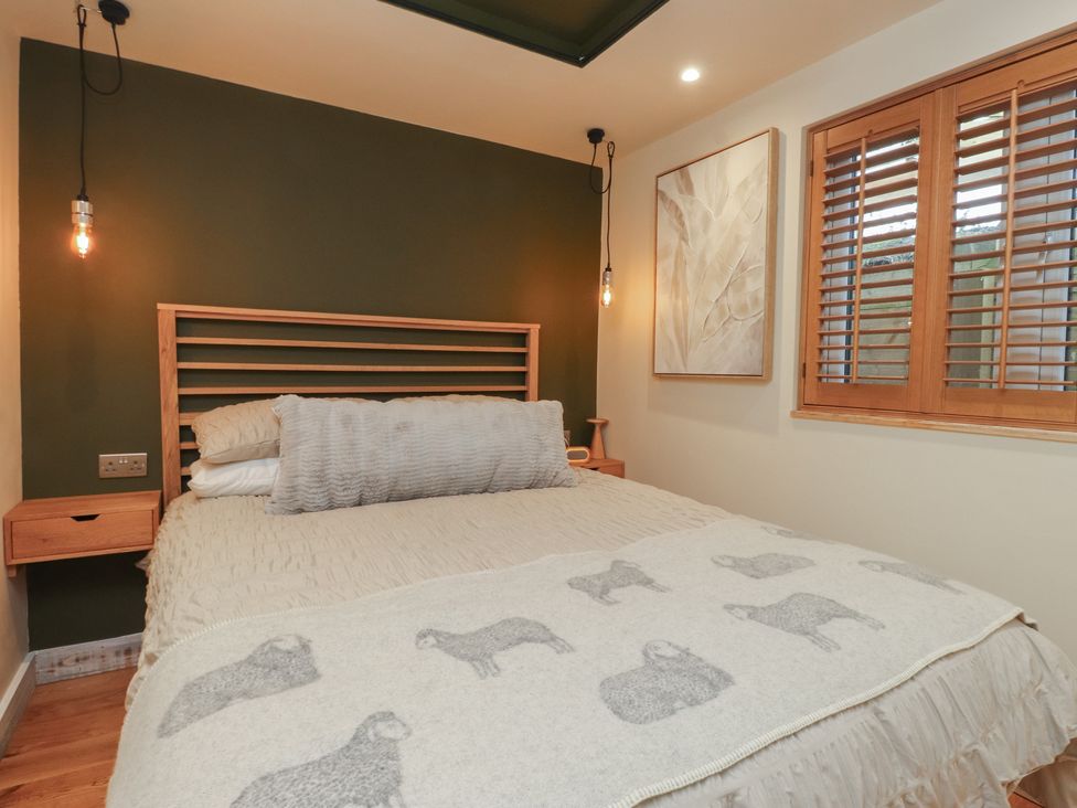 A bedroom with a bed and wall art at Riverside Lodge Afonwen