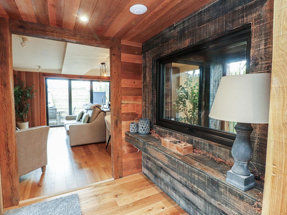 A living room with wooden features and a sofa at Riverside Lodge in Afonwen