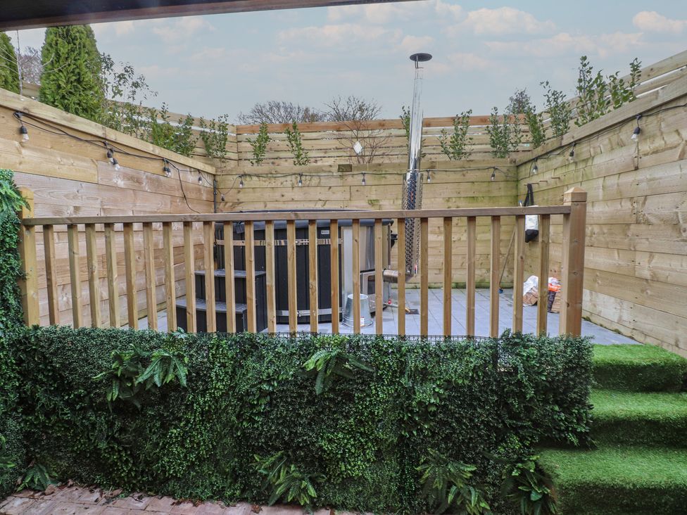 A garden with decking and seating area at Riverside Lodge Afonwen