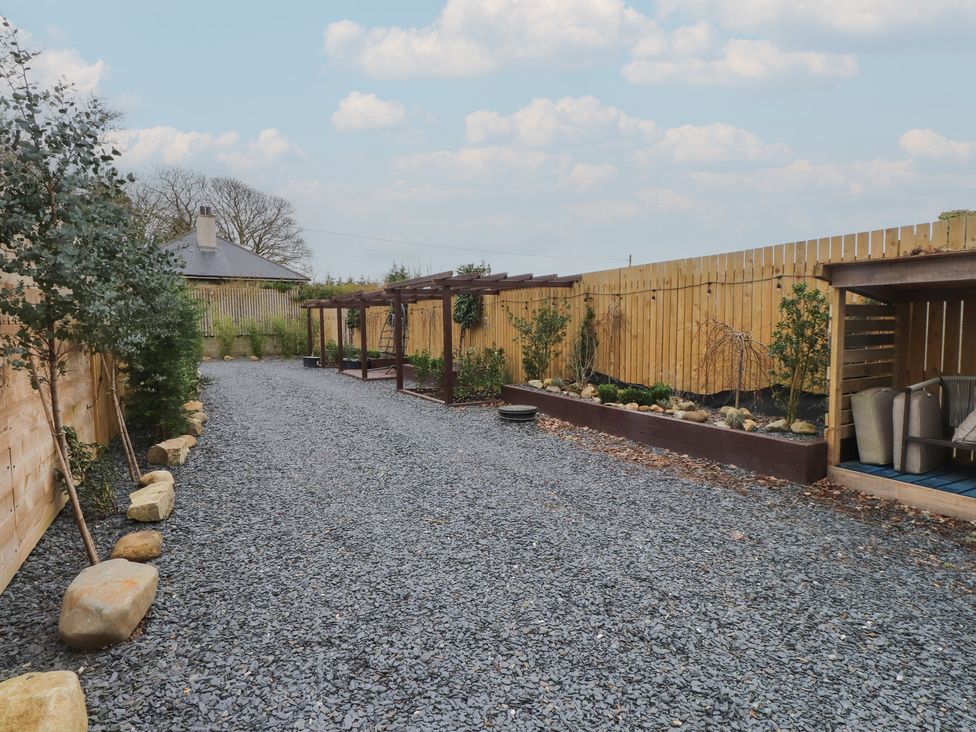 A garden with gravel pathway and planters at Riverside Lodge Afonwen
