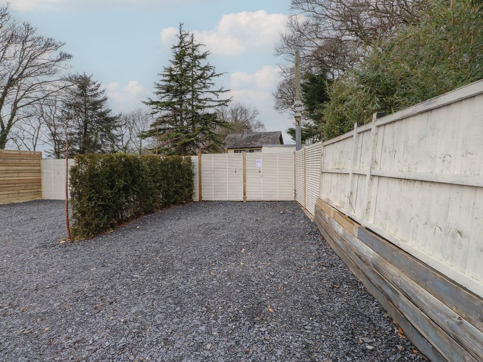 An outdoor area with gravel, hedges, and wooden fence at Riverside Lodge Afonwen