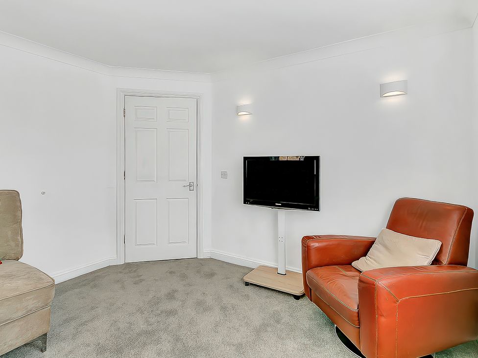 A living room with a TV and a chair at 40 Raleigh Court Sherborne