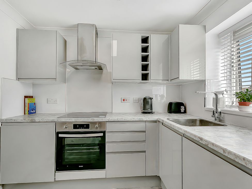 A kitchen with cupboards, oven, stove, kettle, and sink at 40 Raleigh Court Sherborne