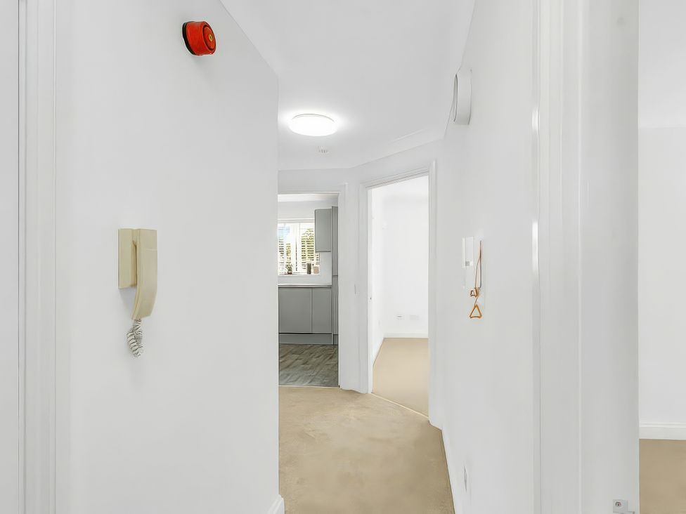 A hallway with a telephone and a view of a kitchen at 40 Raleigh Court in Sherborne