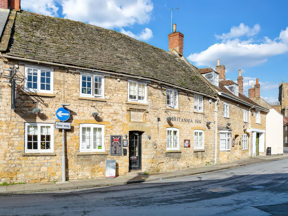 A stone building with windows and signs at the Britannia Inn in Sherborne