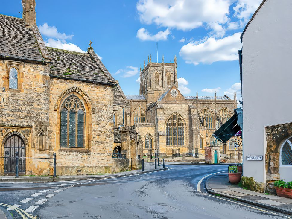 A church with a clock tower and stone buildings at 40 Raleigh Court in Sherborne