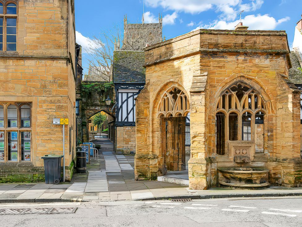 A stone building with an archway and garbage can at 40 Raleigh Court in Sherborne