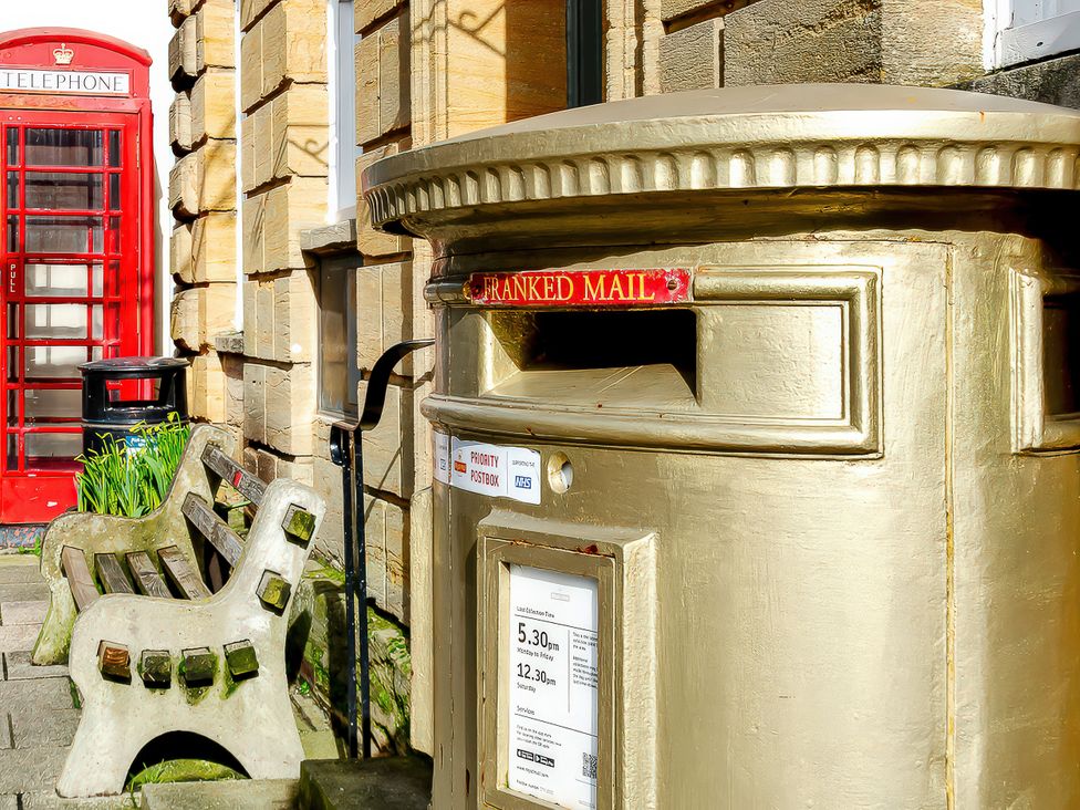 A postbox and telephone booth near a bench at 40 Raleigh Court in Sherborne