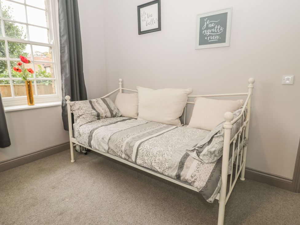 A bedroom with a sofa bed and decorative frames at The Sea Chest in Alnmouth