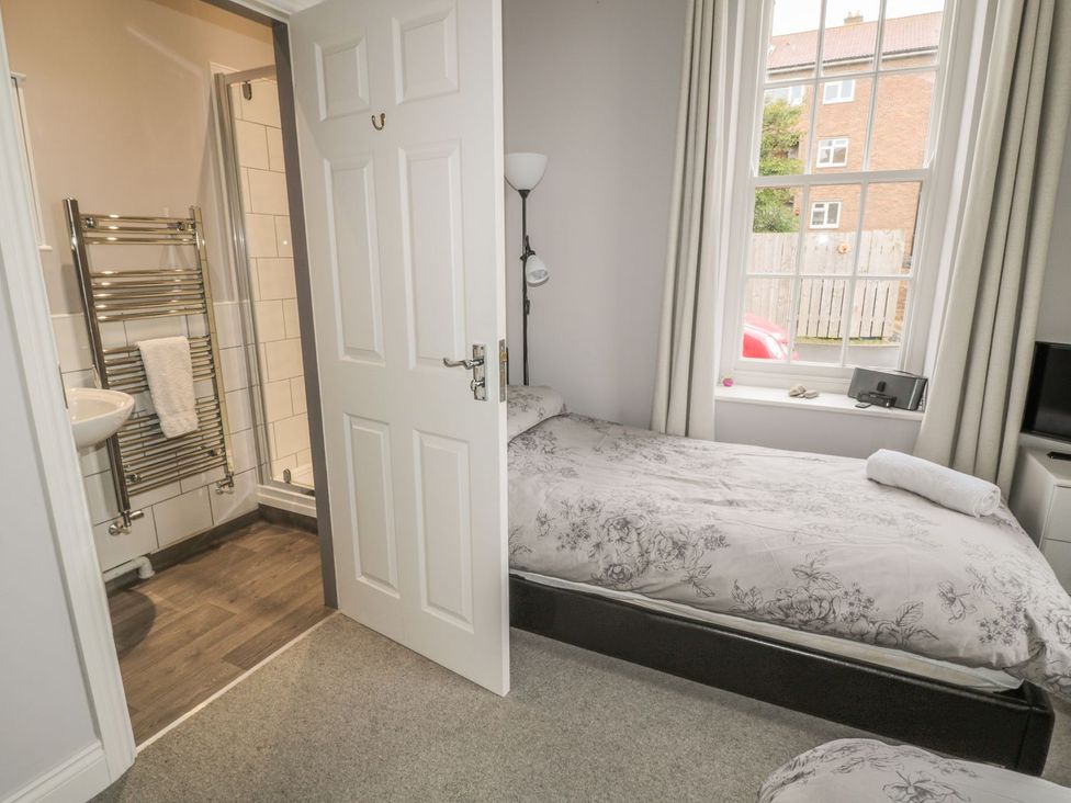 A bedroom with a bed, lamp and bathroom door at The Sea Chest in Alnmouth