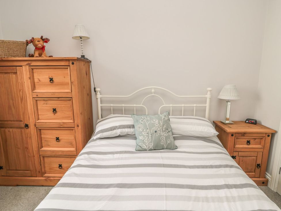A bedroom with a bed and wooden furniture at The Sea Chest in Alnmouth