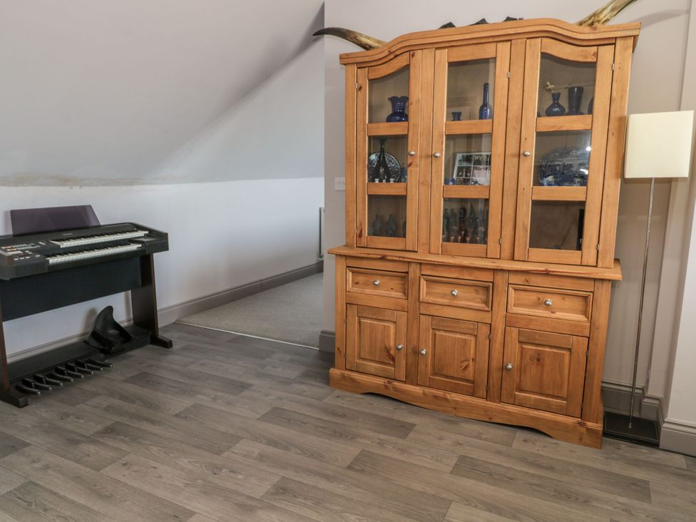 A living room with a keyboard and a wooden cabinet at Sunset Point in Alnwick