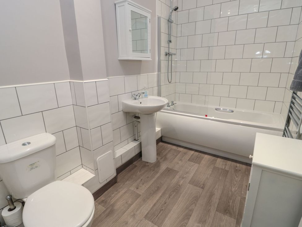A bathroom with a toilet, sink, bathtub, and mirror at Sunset Point in Alnwick
