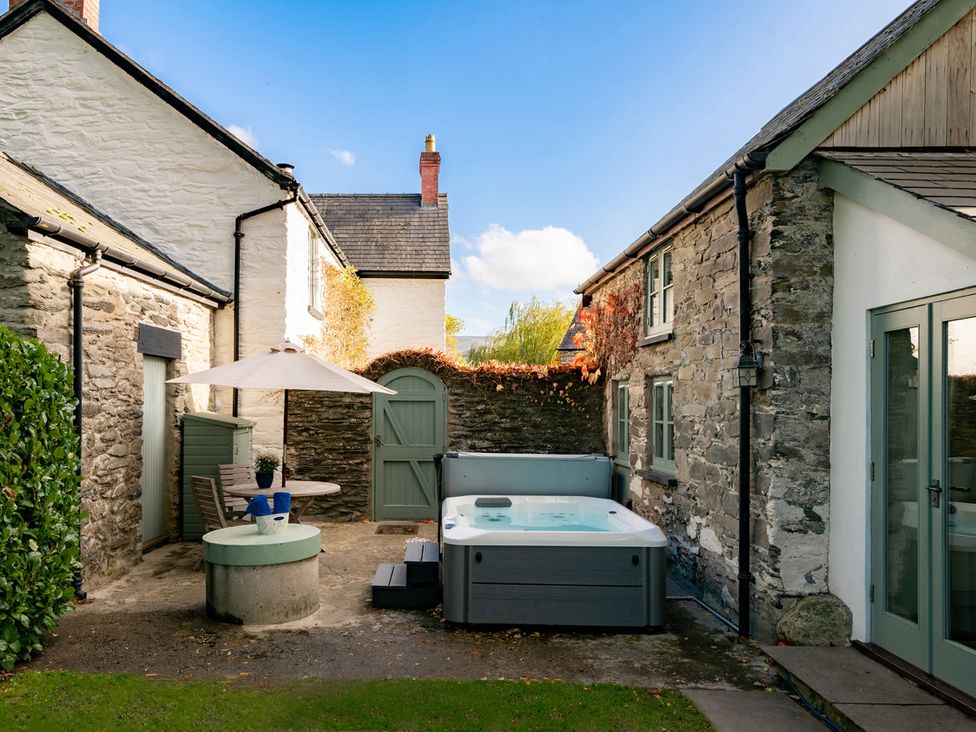 A garden with a hot tub and seating area at Ghillies Cottage in Llandrillo