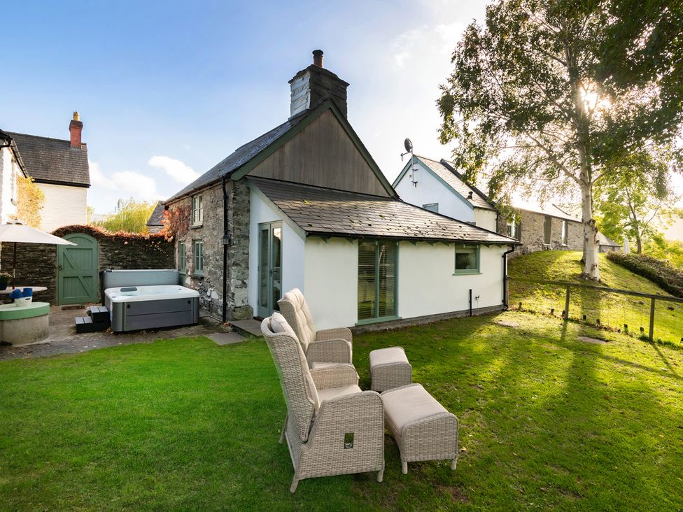 An outdoor area with a hot tub and chairs at Ghillies Cottage in Llandrillo