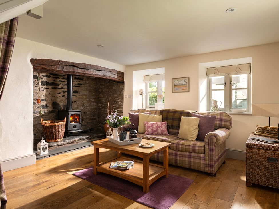 A living room with a fireplace and sofa at Ghillies Cottage Llandrillo