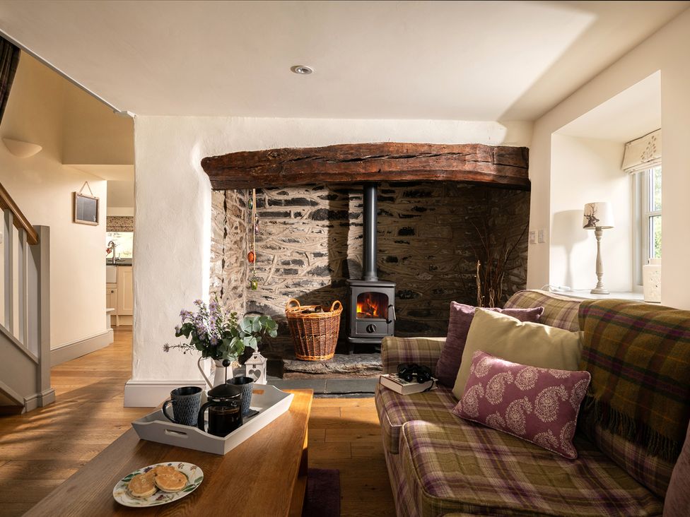 A living room with a fireplace and sofa at Ghillies Cottage in Llandrillo
