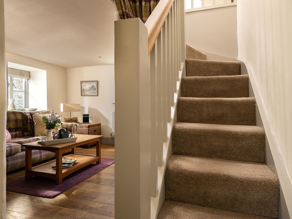 A living room with a staircase and furniture at Ghillies Cottage in Llandrillo