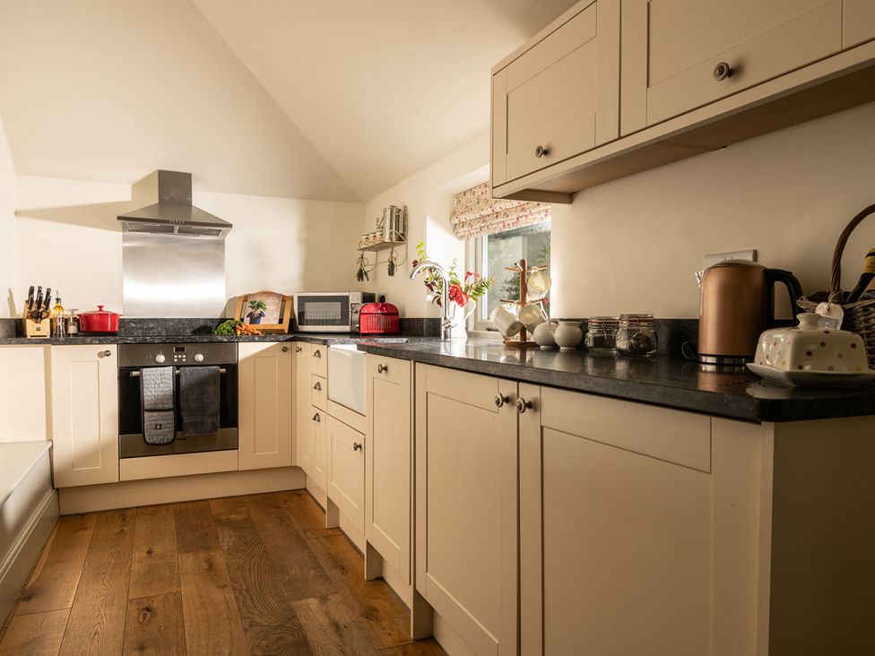 A kitchen with cabinets, stove, and microwave at Ghillies Cottage in Llandrillo