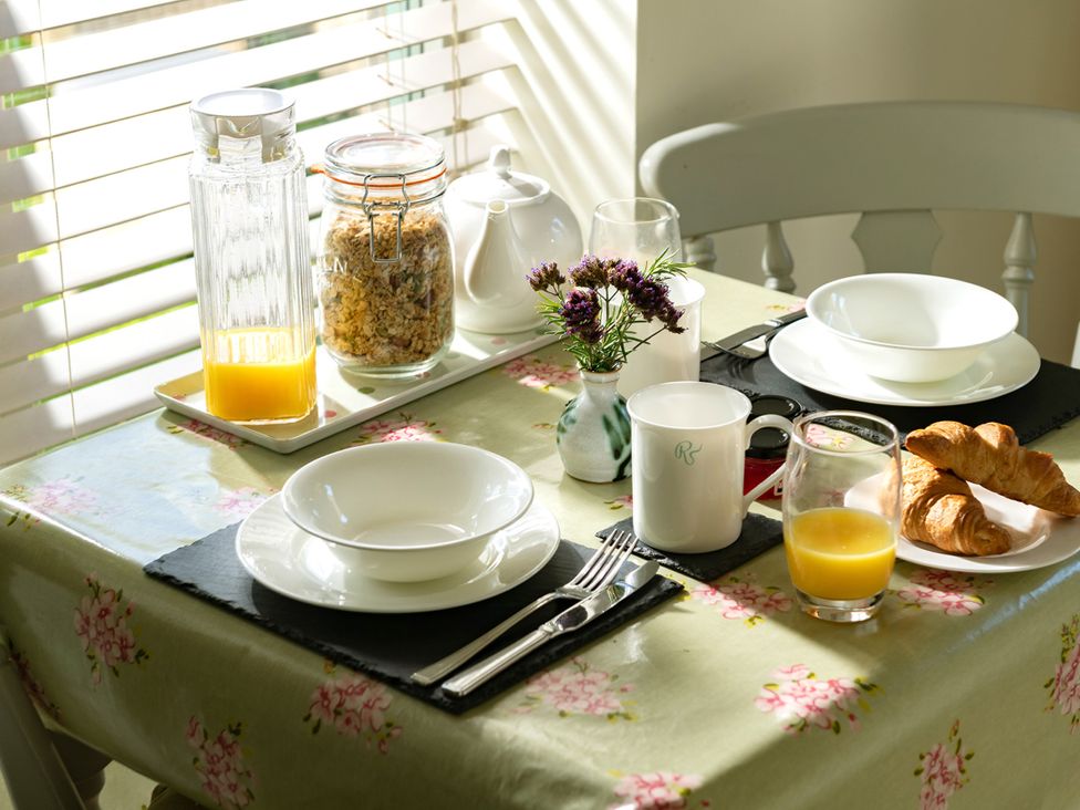 A dining room table set with plates and refreshments at Ghillies Cottage Llandrillo