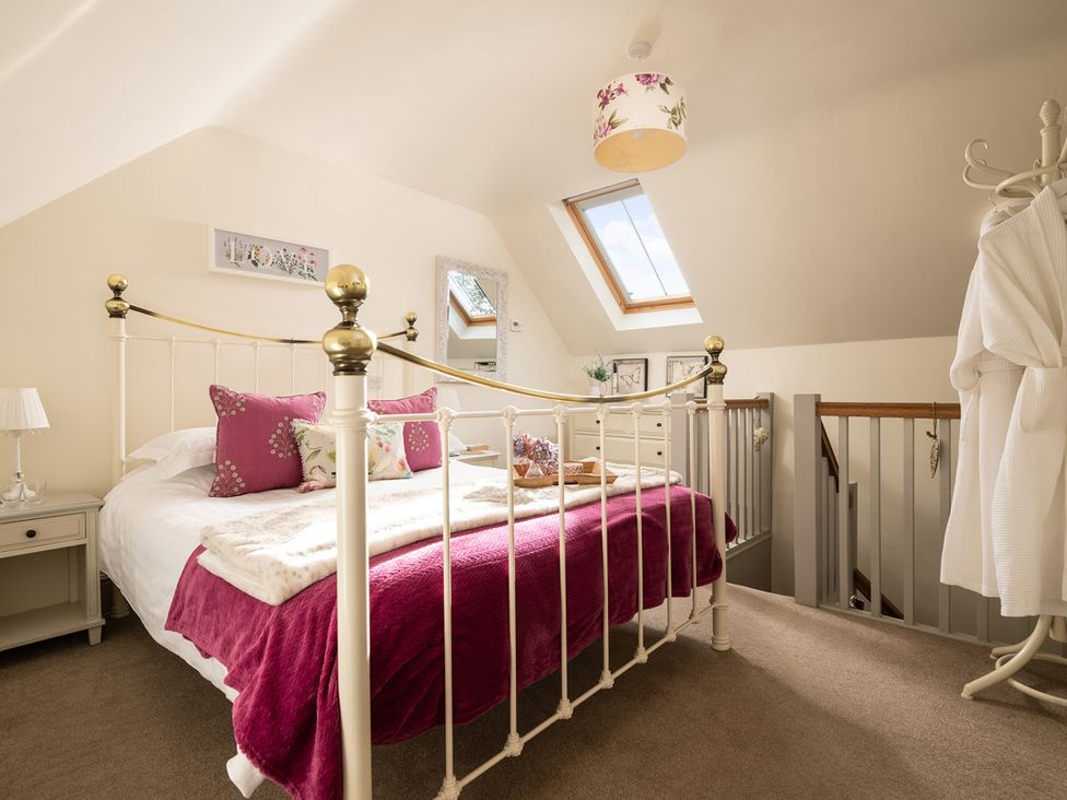 A bedroom with a bed and nightstand at Ghillies Cottage in Llandrillo