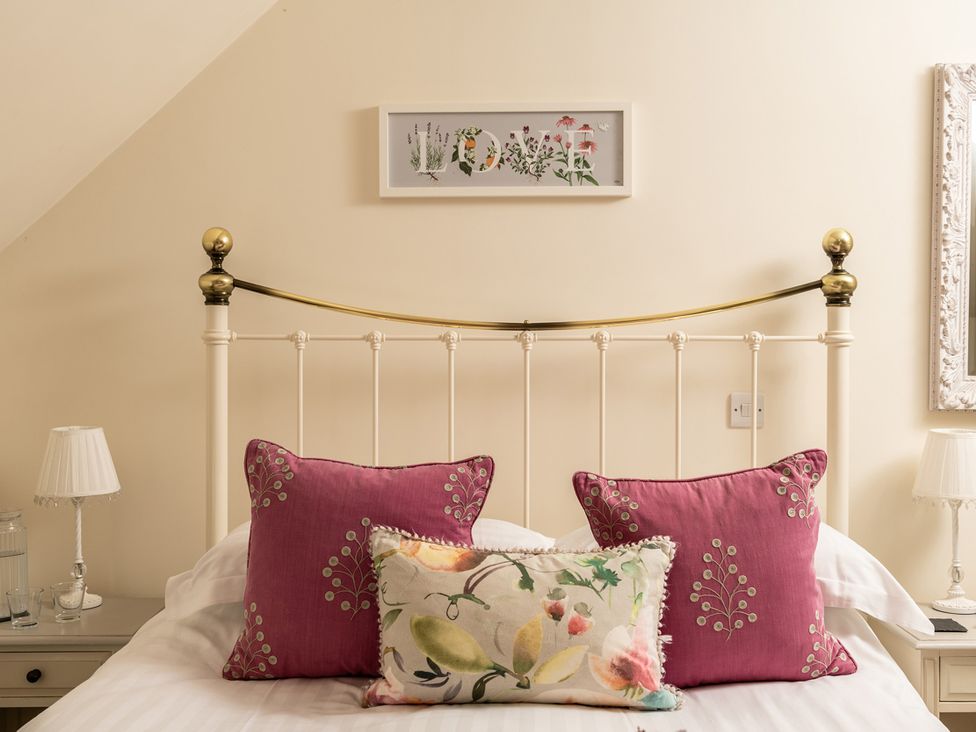 A bedroom with a bed and decorative pillows at Ghillies Cottage Llandrillo