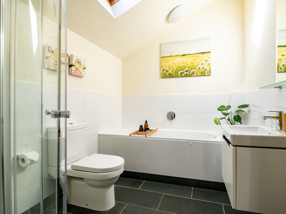 A bathroom with a bathtub and sink at Ghillies Cottage in Llandrillo