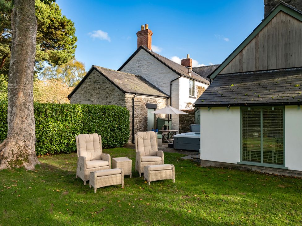 A garden with armchairs and a table at Ghillies Cottage Llandrillo