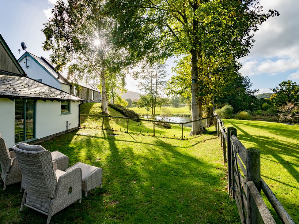 An outdoor area with trees and chairs at Ghillies Cottage in Llandrillo