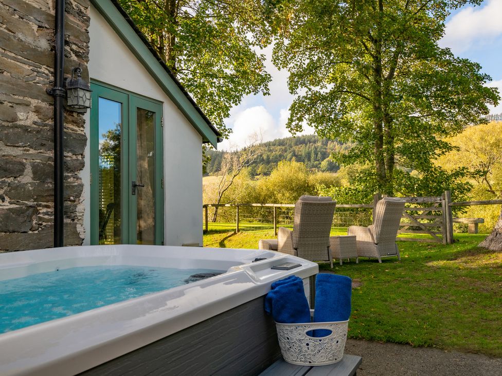 An outdoor space with a hot tub and chairs at Ghillies Cottage in Llandrillo