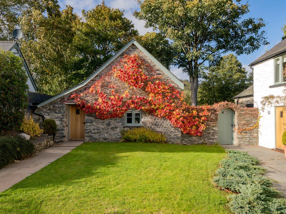 A house with stone walls and a green door in Ghillies Cottage Llandrillo
