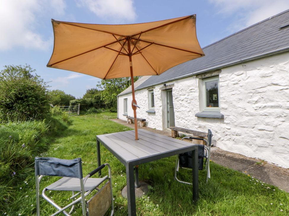 A table with umbrella and chairs outside a cottage at Rhos Y Clegyrn Goodwick