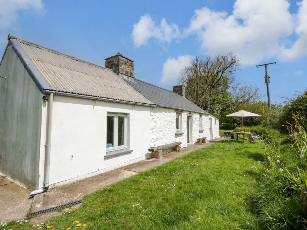 An outdoor area with a cottage, table, and umbrella at Rhos Y Clegyrn Goodwick