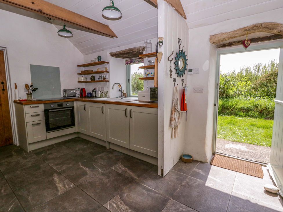 A kitchen with cupboards and a view to the outside at Rhos Y Clegyrn Goodwick