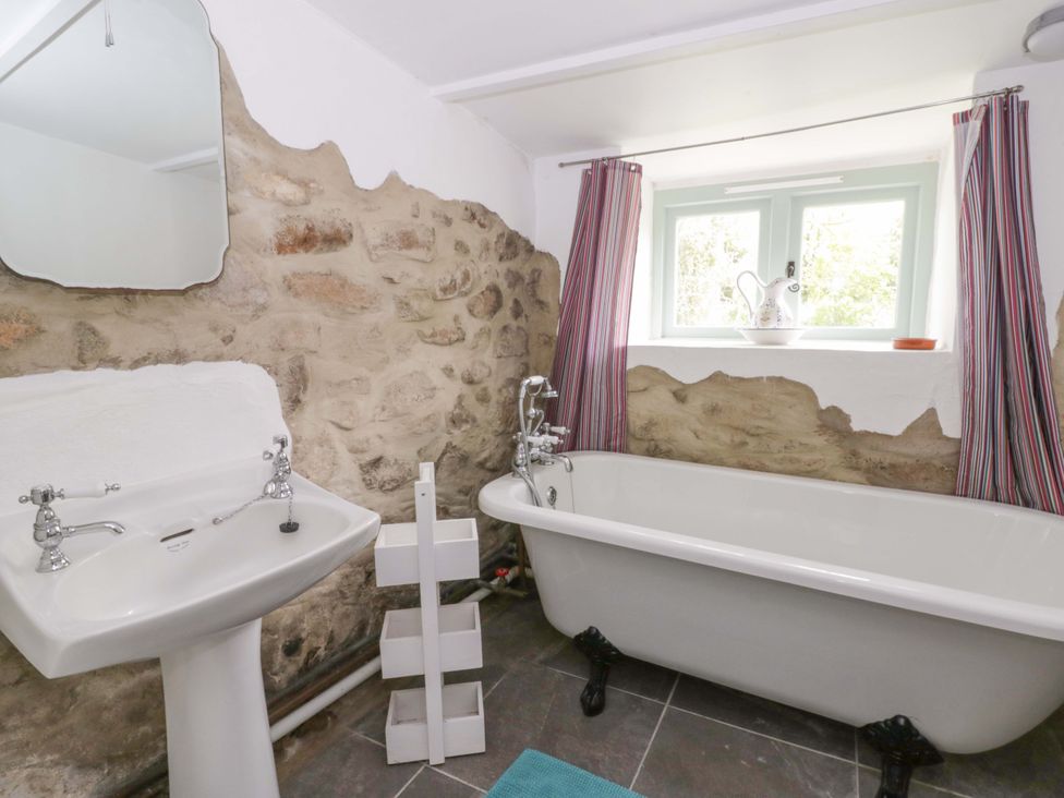 A bathroom with a bathtub, sink, and window at Rhos Y Clegyrn in Goodwick