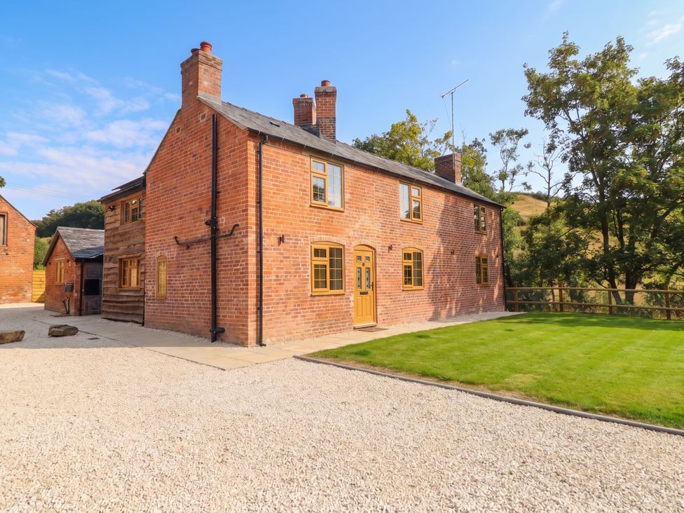 A brick house with a gravel driveway and grass area at Bridge Farm Pontyblew near Chirk