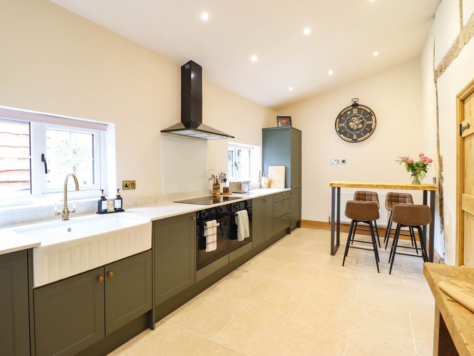 A kitchen featuring a sink, stove, and bar stools at Bridge Farm Pontyblew near Chirk