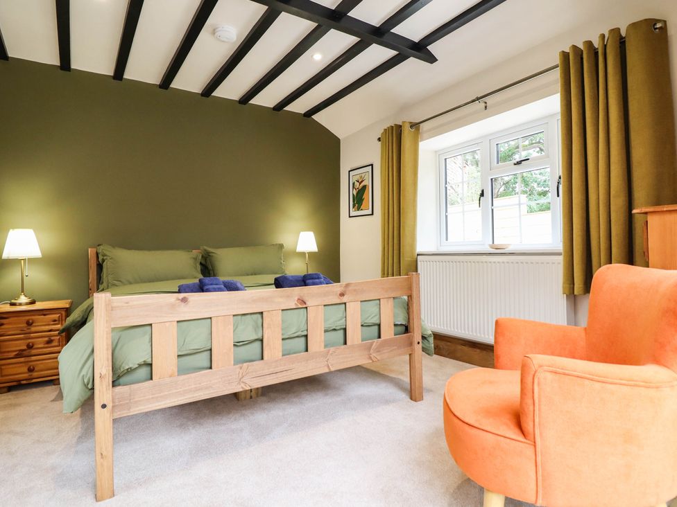 A bedroom with a bed and an armchair at Bridge Farm Pontyblew near Chirk