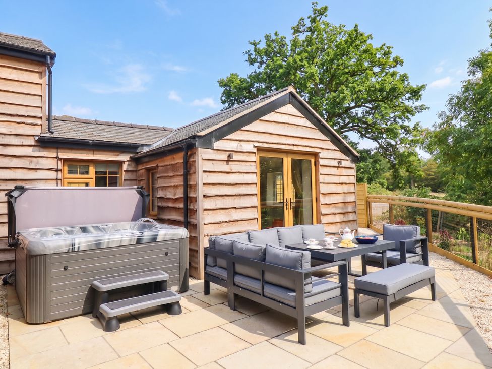 An outdoor area with a hot tub and seating at Bridge Farm Pontyblew near Chirk