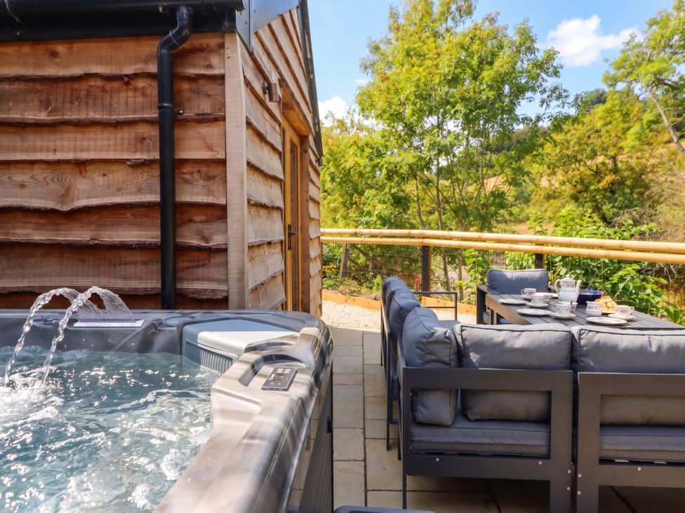 An outdoor area with a hot tub and dining set at Bridge Farm Pontyblew near Chirk