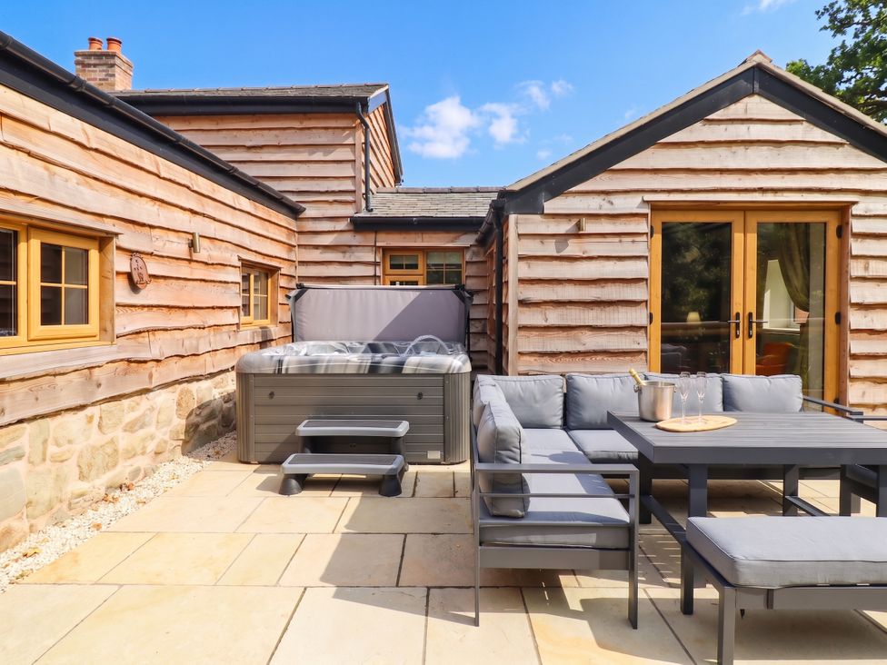 An outdoor area with a hot tub and sofa at Bridge Farm Pontyblew near Chirk