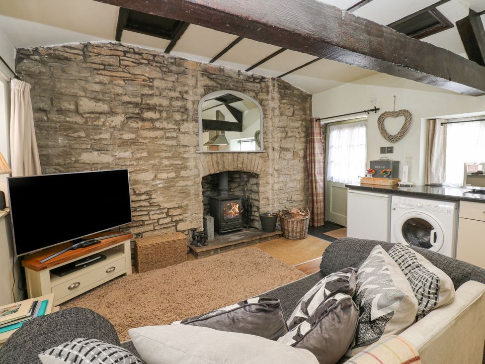 A living room with a fireplace and television at In & Out Cottage Leyburn